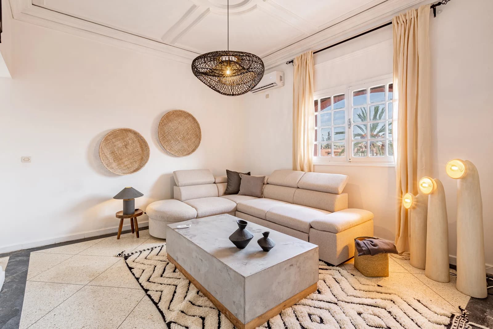 Light-filled living room with woven decor, warm beige curtains and patterned rug