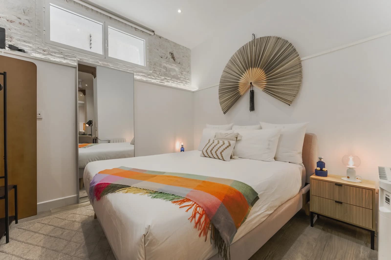 Second bedroom with sun-fan wall art and colour-block throw