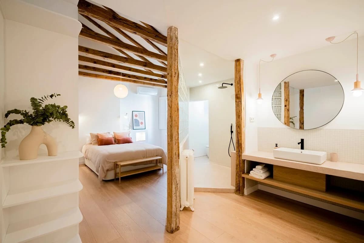 Bedroom and ensuite vignette under exposed beams with circular mirror