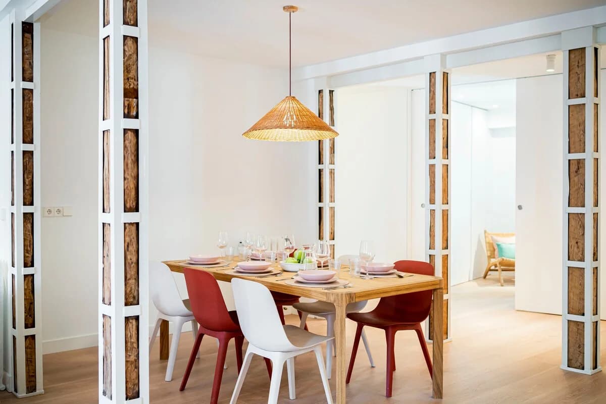 Oak dining table framed by twin reclaimed-beam screens and rattan pendant
