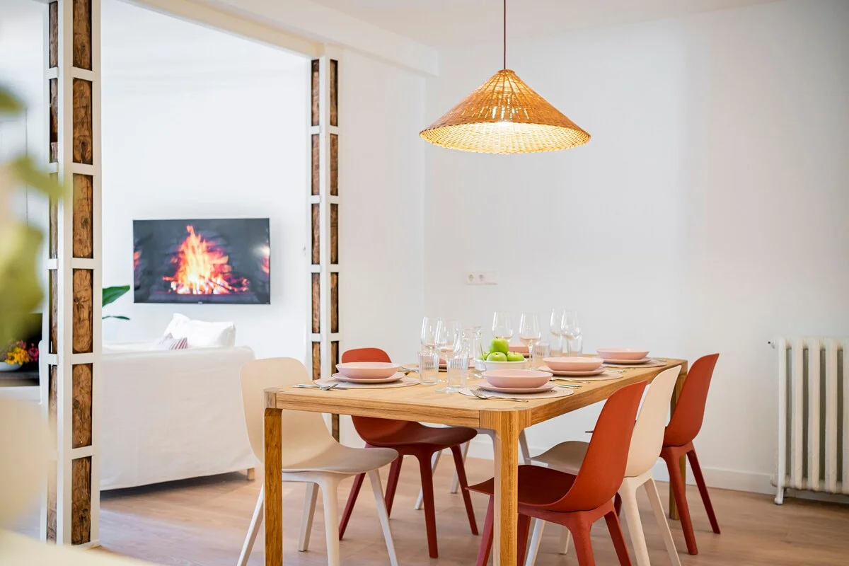 Dining table set for six with conical pendant and fireplace beyond
