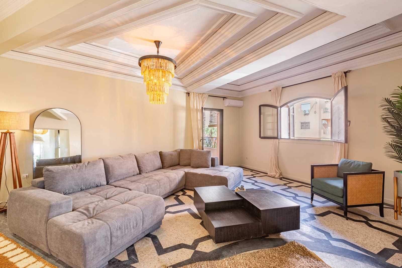 Grand living room under coffered ceiling with crystal chandelier and patterned floor