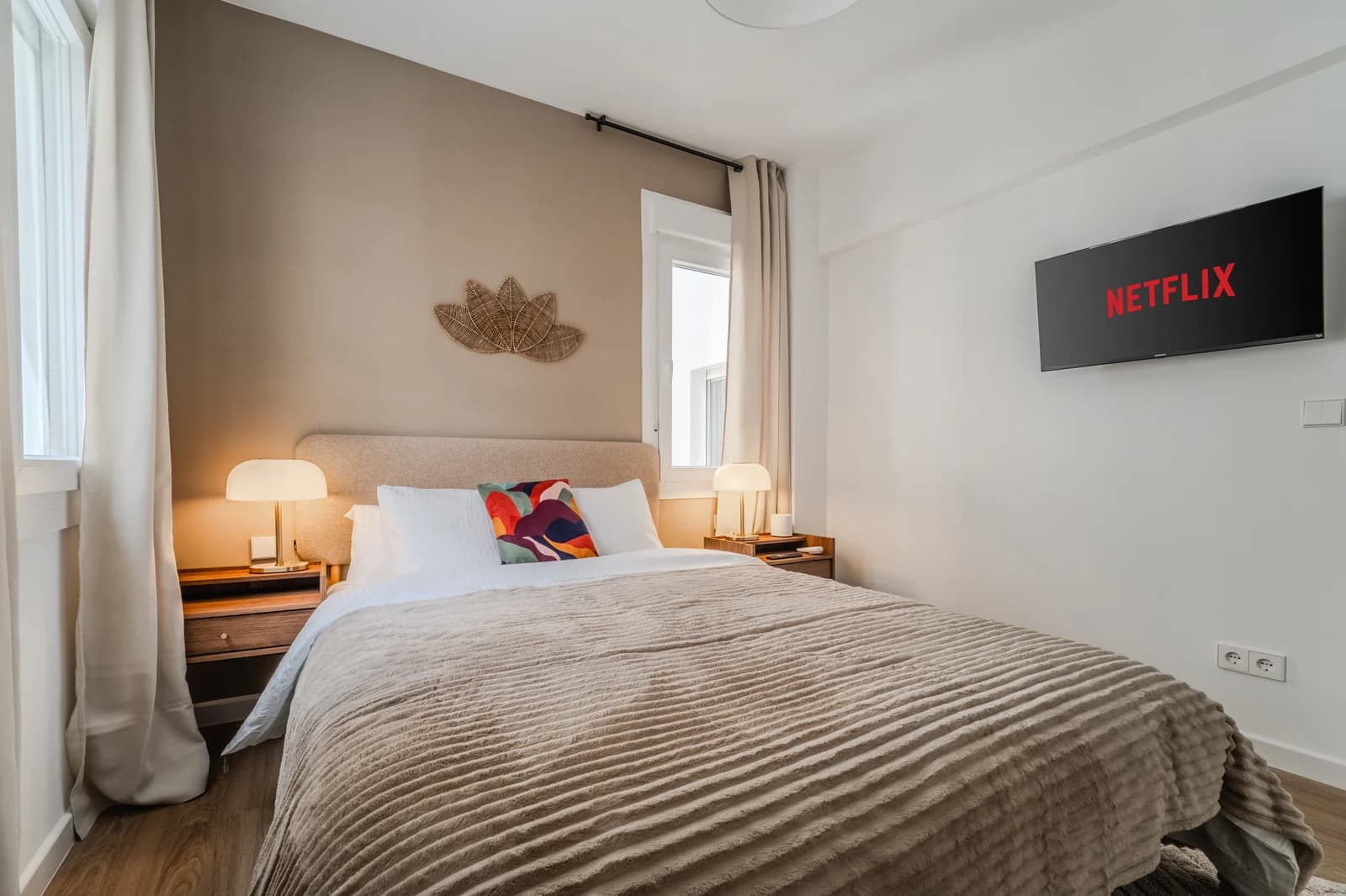 Master bedroom with taupe accent wall, twin lamps and woven art
