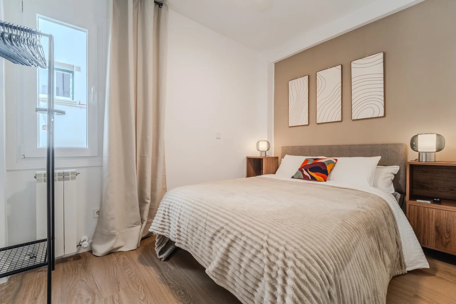 Second bedroom with line-art triptych and natural light from balcony