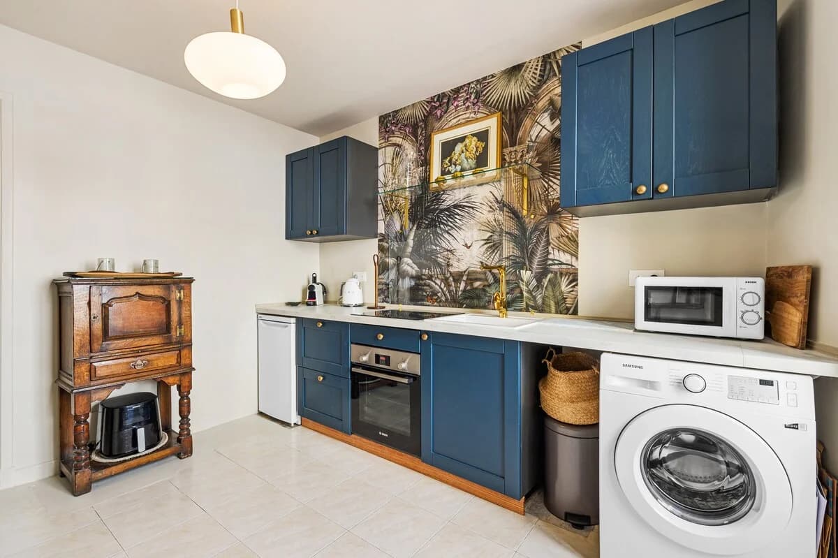 Tropical-wallpaper kitchen with navy cabinetry and antique side cabinet