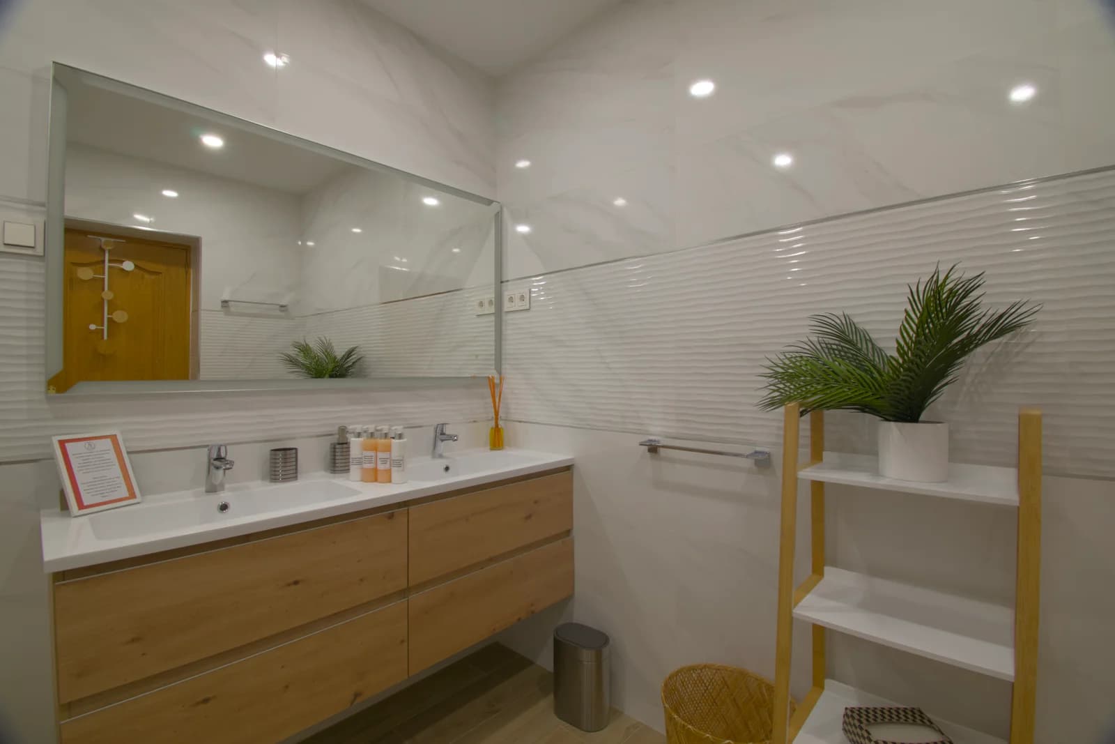 Wide marble bathroom with double sink and floating wood vanity