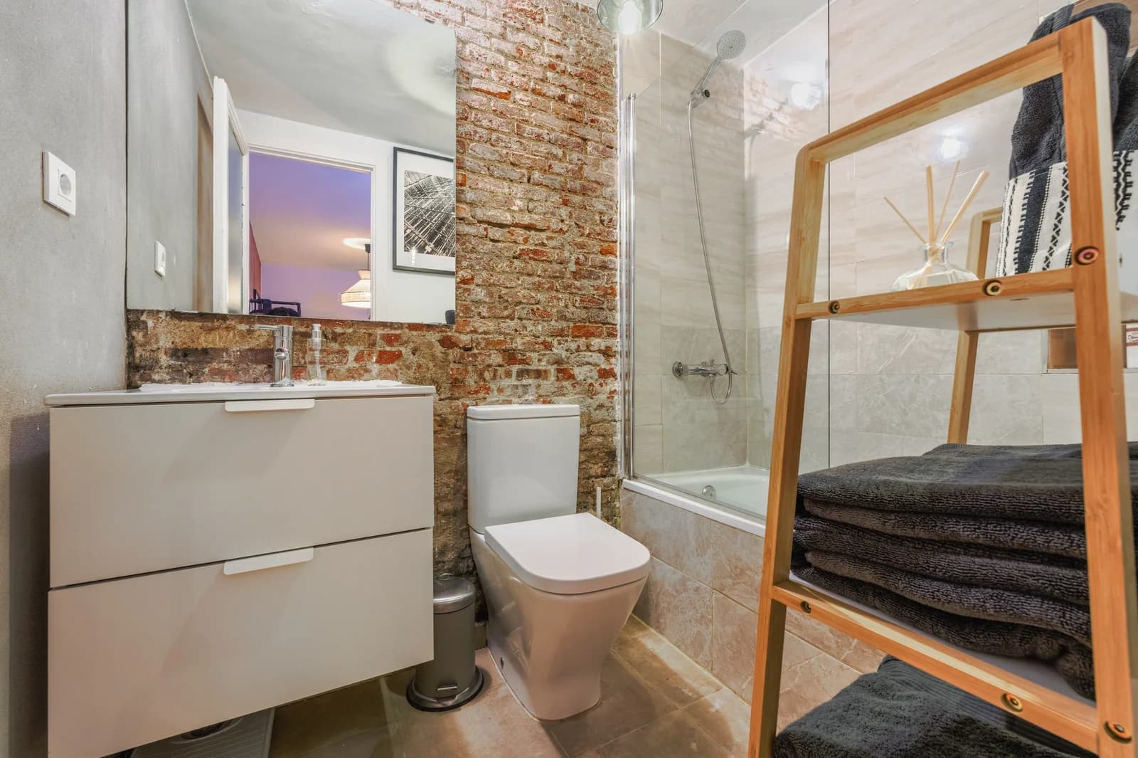 Bathroom with exposed-brick column, bathtub and wooden ladder shelf