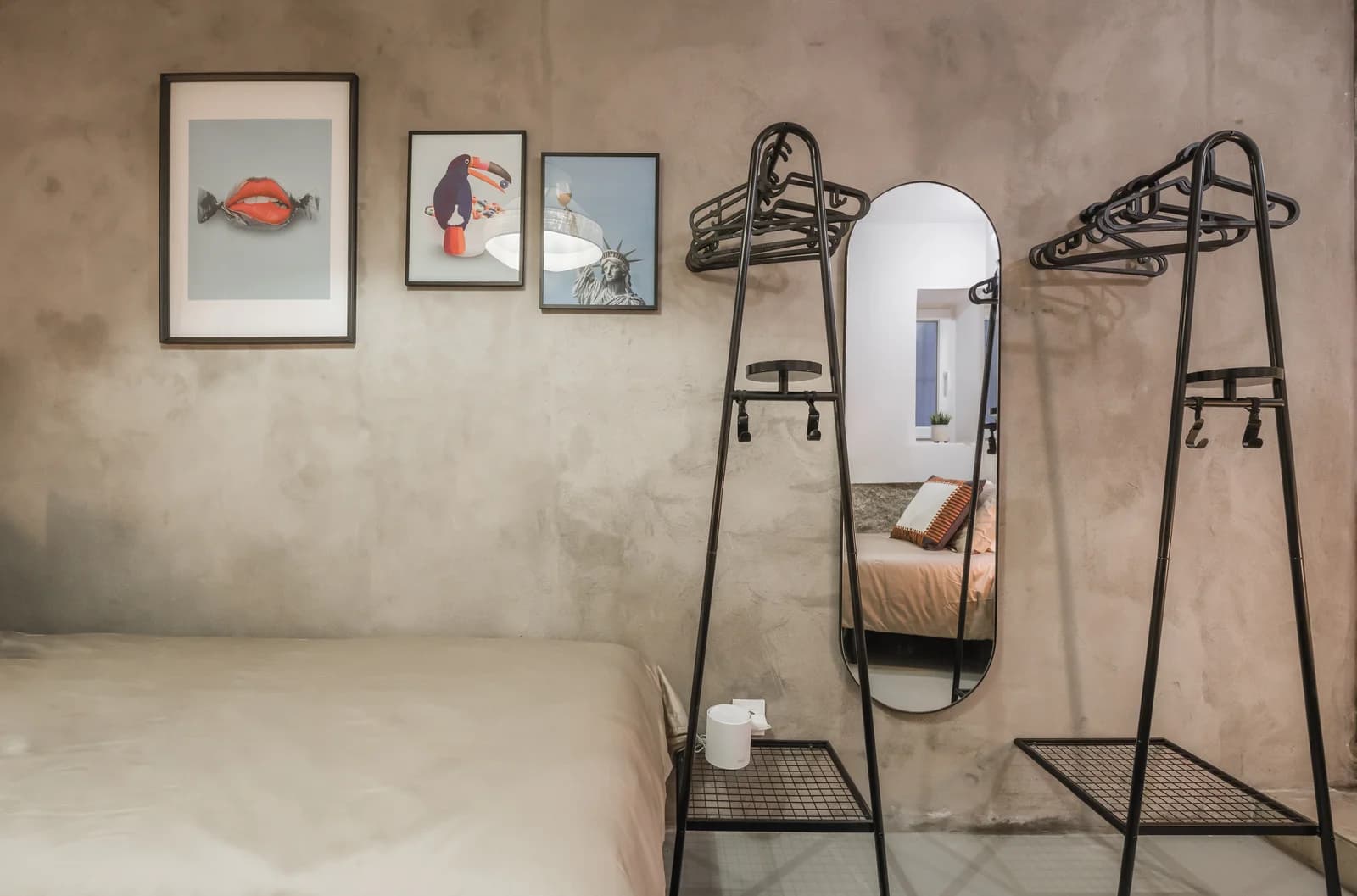 Concrete-walled bedroom with industrial mirror stands and gallery prints