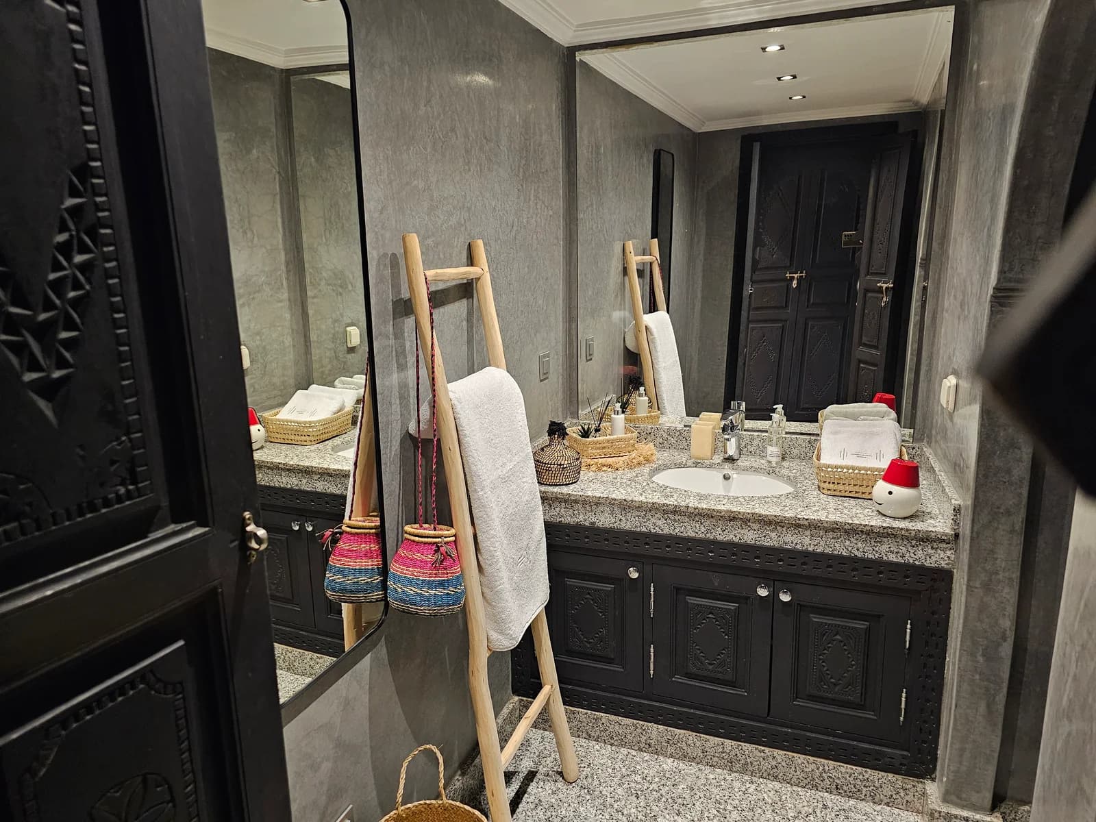Vanity bathroom with carved cabinetry, ladder towel rack and woven baskets