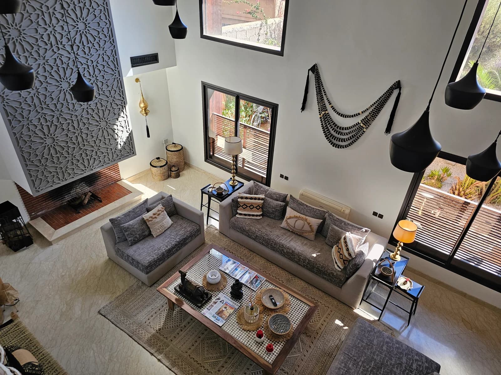 Aerial view of double-height living room with carved Moroccan screen and pendant cluster